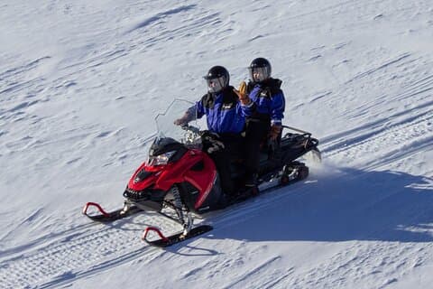 Two persons share the snowmobile with the possibility to switch drivers halfway