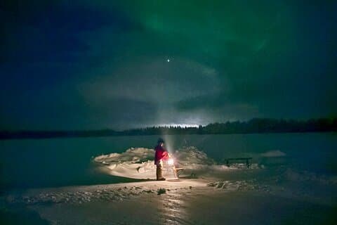 Kicksledding on a frozen Arctic lake under the Northern Lights near Levi.