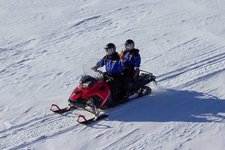 Two adults ride on one snowmobile with opportunity to switch drivers