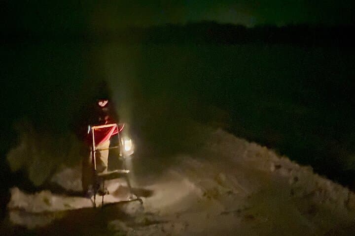 Guided night kick sled ride on a frozen lake, lit by lanterns and stars.
